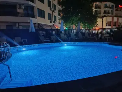 a large swimming pool with blue water at night at Aquamarin Studio B - Słoneczny Brzeg-Nesebyr in Sunny Beach
