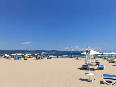 a beach with chairs and umbrellas and people on it at Aquamarin Studio B - Słoneczny Brzeg-Nesebyr in Sunny Beach