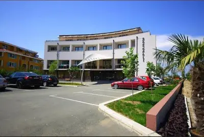 a building with cars parked in a parking lot at Galqna in Sozopol