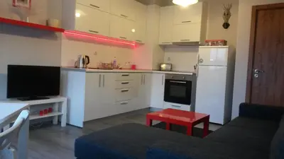 a kitchen with white cabinets and a red stool in a room at South Beach Apartments in Obzor