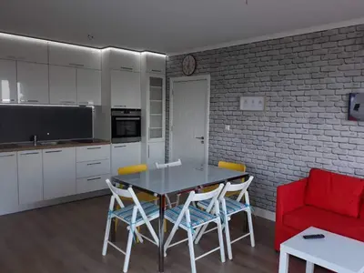 a kitchen with a table and chairs and a red couch at South Beach Apartments in Obzor