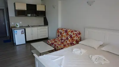 a room with a bed and a chair and a kitchen at Privately owned Studios Bora Bora in Nesebar