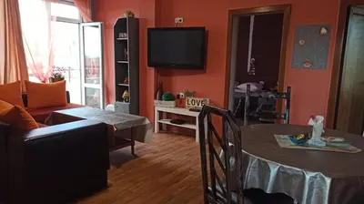 a living room with a table and a tv at Панорама in Pomorie
