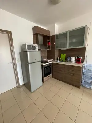 a kitchen with a white refrigerator and wooden cabinets at Flat on the beach in Chernomorets