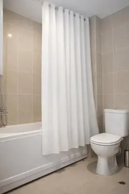 a bathroom with a white shower curtain and a toilet at Luxury Studio in Sunny Beach with Pool, 5 Mins Walk to Beach in Sunny Beach