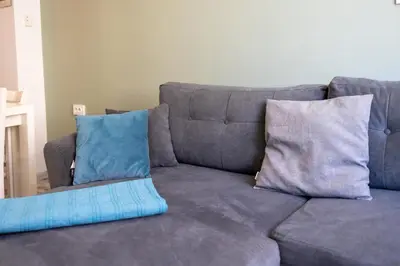 a gray couch with two blue pillows on it at Bright City-Center Flat for 4 Guests in Varna City