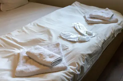 a white bed with towels and shoes on it at Bright City-Center Flat for 4 Guests in Varna City