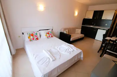 a bedroom with a white bed and a kitchen at Sunset Beach 3 - Menada Apartments in Sunny Beach