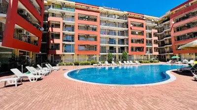 a large apartment building with a swimming pool and chairs at Sunset Beach 3 - Menada Apartments in Sunny Beach
