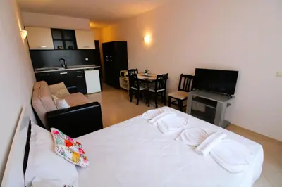 a living room with a white bed and a kitchen at Sunset Beach 3 - Menada Apartments in Sunny Beach