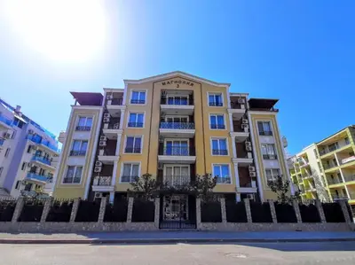 a tall yellow building with a fence in front of it at Magnolia 3 - Menada Apartments in Sunny Beach
