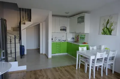 a kitchen with green cabinets and a white table and chairs at Large Two Floor Apartment in Byala