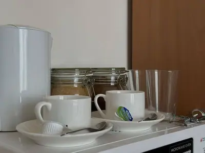 two cups and saucers on top of a microwave at Слънчев Бряг Какао с басейн плаж in Sunny Beach