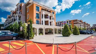 a parking lot with cars parked in front of a building at Premier Fort Beach Aparthotel - Sunny Beach in Sveti Vlas