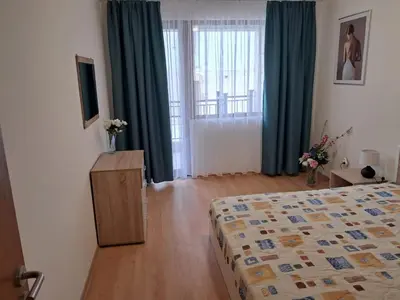 a bedroom with a bed and a dresser and a window at Apartment in Byala Vista Compex in Byala