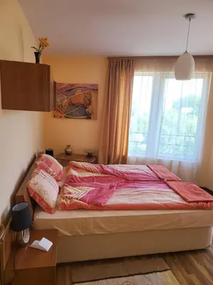 a bedroom with a bed with pink sheets and a window at Luxury apartment opposite Kakao in Sunny Beach