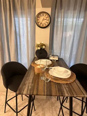 a wooden table with plates and wine glasses and a clock at Top Center Apartment in Varna City