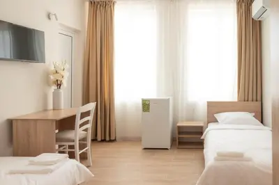 a bedroom with two beds and a table and a desk at Леглото in Topoli