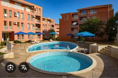 a swimming pool in front of a building with umbrellas at Слънчев бряг Sunny day 6 One bedroom apartment in Sunny Beach