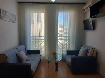 a living room with two blue couches and a window at Слънчев бряг Sunny day 6 One bedroom apartment in Sunny Beach
