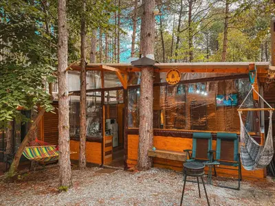 a cabin in the woods with a hammock and a swing at Бунгало Борче in Burgas City