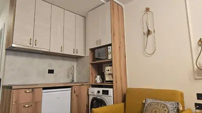 a kitchen with white cabinets and a washer and dryer at Vladan apartments in Sozopol