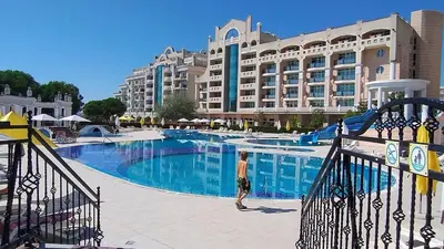 a man standing next to a swimming pool in a hotel at Specious apartment near beautiful beach Pomorie in Pomorie