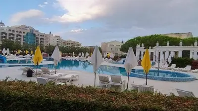 a swimming pool with chairs and umbrellas in a resort at Specious apartment near beautiful beach Pomorie in Pomorie
