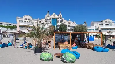 people sitting on the beach in front of a hotel at Specious apartment near beautiful beach Pomorie in Pomorie