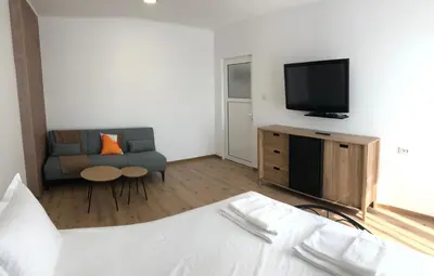 a room with a bed and a couch and a television at Calendula in Burgas City