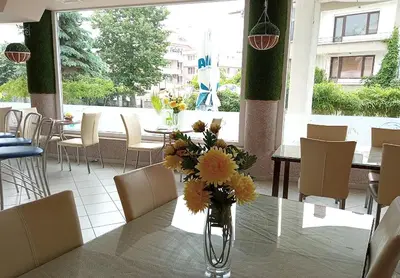 a vase of flowers on a table in a restaurant at Hotel Andre in Burgas City