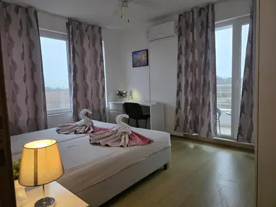 a bedroom with a bed and a desk and windows at Perla View Apartment in Primorsko