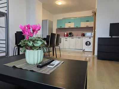 a vase with pink flowers on a table in a living room at Perla View Apartment in Primorsko