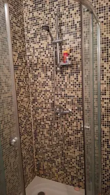 a shower in a bathroom with tiled walls at Апартамент in Burgas City