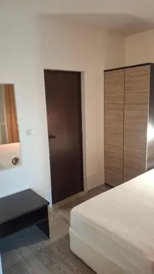 a bedroom with a bed and a wooden cabinet at Апартамент in Burgas City