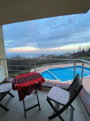 a balcony with two chairs and a table and a swimming pool at Beautiful family appartment with sea view in Byala