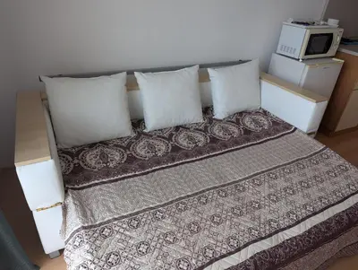 a bedroom with a bed with pillows and a microwave at Sunny Day 5 in Tŭnkovo