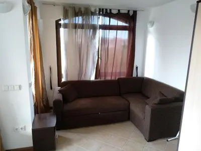 a living room with a brown couch in front of a window at Oasis Resort&Spa Lozenets Studio 2 in Lozenets