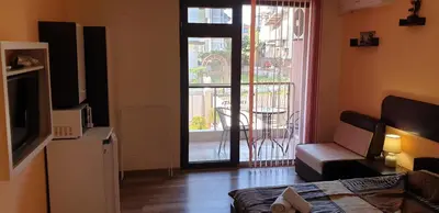 a living room with a television and a door to a balcony at Морската Къща in Tsarevo