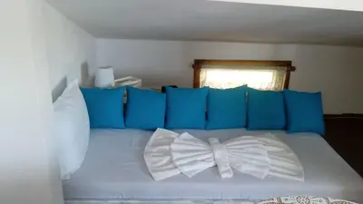 a white bed with blue pillows and a bow tie on it at Rali Apartments in Kiten