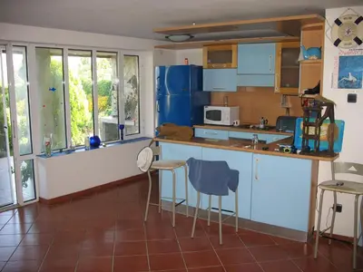 a kitchen with blue cabinets and a counter with chairs at Villa Magnet in Lozenets