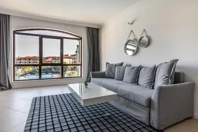 a living room with a couch and a large window at Oasis Beach Club in Lozenets