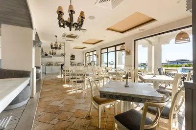 a restaurant with tables and chairs and windows at Oasis Beach Club in Lozenets