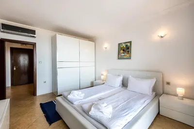 a bedroom with a large white bed with white sheets at Oasis Beach Club in Lozenets