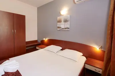 a bedroom with a white bed and a wooden headboard at Guesthouse Kirov in Ravda