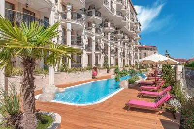 a hotel with a pool and chairs and a building at Harmony Suites Saint Vlas in Sveti Vlas