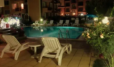 a swimming pool with two chairs and a table next to it at Aquaria Holiday Apartments in Sunny Beach