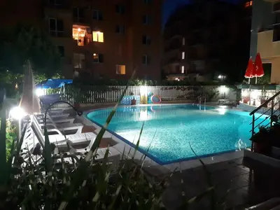 a swimming pool at night with chairs and a volley ball at Aquaria Holiday Apartments in Sunny Beach