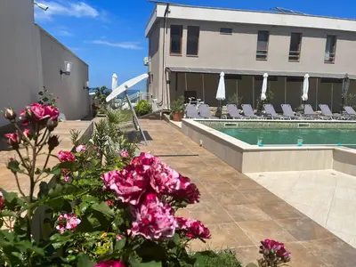 a building with a swimming pool and pink flowers at Melia Mar in Sozopol
