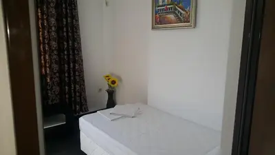 a white table with a vase of flowers on it at Central Beach GUEST ROOMS in Burgas City